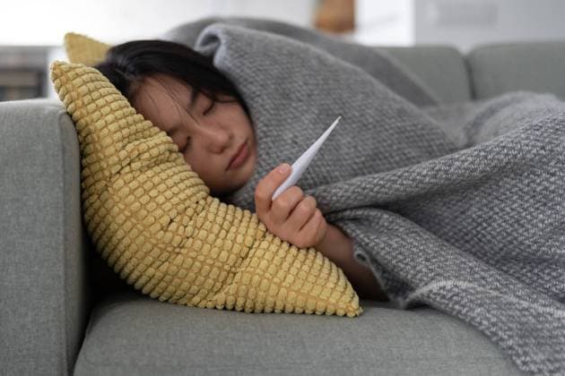 Sick Asian girl lying on sofa wrapped in blanket hold thermometer after infection, covid-19 outbreak Sick Asian girl lying on sofa, wrapped in blanket and holds thermometer to measure body temperature. Unhealthy Korean woman infected with new strain of flu needs hospitalization. New covid-19 outbreak ,model released, Symbolfoto Copyright: xZoonar.com DmitriixMarchenkox 22036093 ,model released, Symbolfoto ,property released