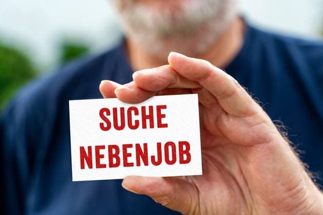 August 21, 2024: Old man holding a sign with the inscription: Looking for part-time job. PHOTOMONTAGE *** Alter Mann hält ein Schild mit Aufschrift: Suche Nebenjob. FOTOMONTAGE