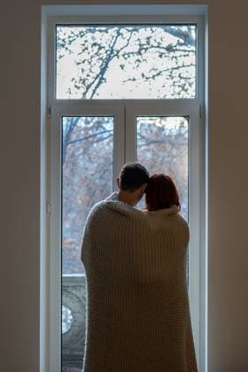 Couple wrapped in blanket looking out window Rear view of couple wrapped in blanket looking out window cuddling and dreaming about future, family man and woman warming under plaid, feeling cozy at home during cold wet weather ,model released, Symbolfoto Copyright: xZoonar.com DmitriixMarchenkox 22051356 ,model released, Symbolfoto ,property released