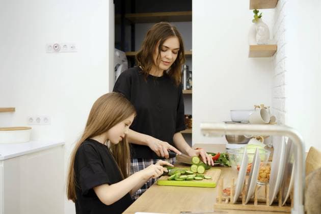 Eine junge Familie bereitet einen Salat aus frischem Gemüse zu. Mutter und Tochter schneiden frische Gurken aus dem eigenen Garten A young family prepares a salad from fresh vegetables. Mother and daughter cut fresh cucumber grown in their garden Copyright: imageBROKER AlekseixIsachenko ibxfbm11002204.jpg ,model released, Symbolfoto ,property released