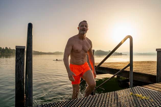 Shirtless senior man disembarking from lake at sunrise model released, Symbolfoto, DIGF21635