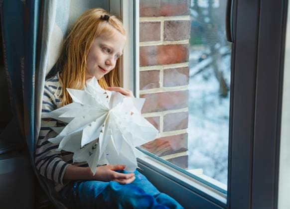 Girl holding christmas star and looking through window at home model released, Symbolfoto property released, IHF02075