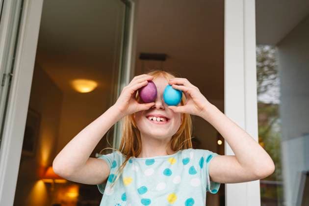 Happy girl covering eyes with colored easter eggs at home model released, Symbolfoto property released, IHF02079