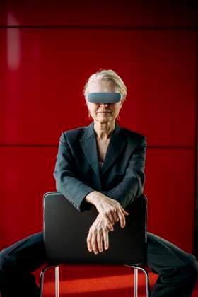 Creative Highlights Symbolbilder Businesswoman wearing virtual reality headset sitting on chair near red wall model released, Symbolfoto property released, JOSEF25593
