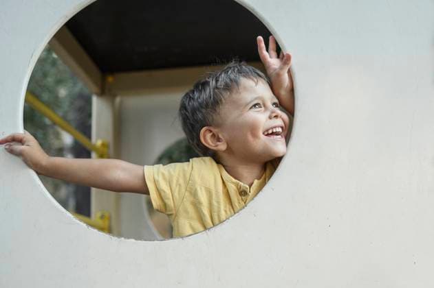 Creative Highlights Symbolbilder Smiling cute boy looking from playing equipment at playground model released, Symbolfoto, ANAF03568