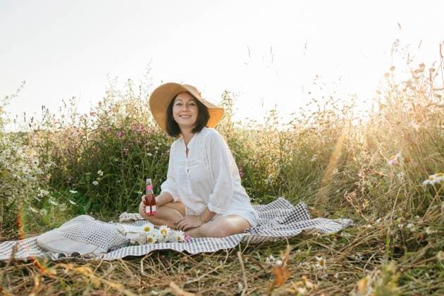 Creative Highlights Symbolbilder Woman wearing sun hat holding wine bottle and sitting in daisy field model released, Symbolfoto, ELMF00705