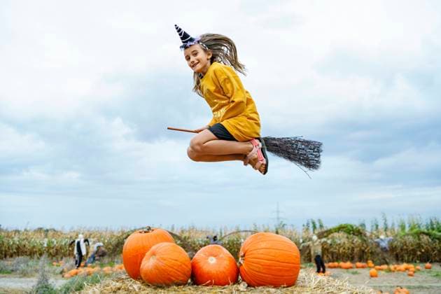 Creative Highlights Symbolbilder Girl wearing witch costume flying on broomstick in pumpkin patch model released, Symbolfoto, NSTF00322