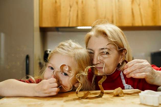 Granddaughter and grandmother looking through cookie cutters in kitchen model released, Symbolfoto property released, NSTF00338