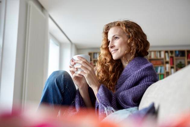 Thoughtful woman sitting on sofa and holding coffee cup at home model released, Symbolfoto property released, RBF09385