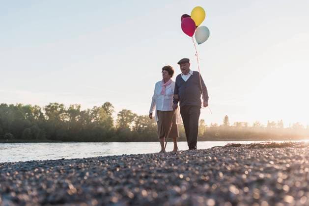 Creative Highlights Symbolbilder Senior couple walking with balloons near river under sky model released, Symbolfoto, UUF32562