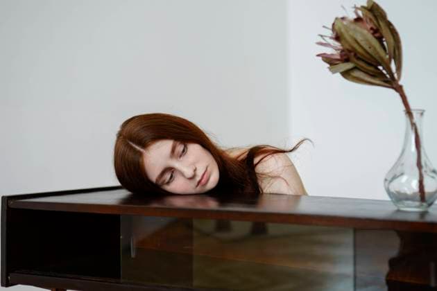 Creative Highlights Symbolbilder Woman leaning on table and looking at dried flowers in home model released, Symbolfoto, VCF00160