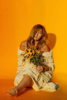 Creative Highlights Symbolbilder Woman holding yellow flowers in front of a yellow backdrop Tulsa, Oklahoma, United States R_KRRY240821-1521128-01 ,model released, Symbolfoto