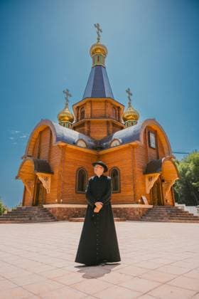 Creative Highlights Symbolbilder Catholic priest, male, dressed in traditional black attire, standing outside the ornate Orthodox Catholic church in Altea, Valencia, Spain, under bright blue skies. He is looking at the camera. Model Released AlvaroMontero_ID23219_675189_023 Copyright: xAlvaroxMonterox