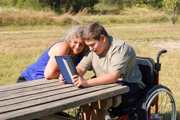 MR_ID23315_18091_OriolRieraTudela.jpg, MR_ID23315_18090_NuriaTudelaMartinez.jpg A young boy with cerebral palsy, seated in a wheelchair, bonds with his mother outdoors over a digital tablet Model Released ClaudiaAyuso_ID23315_677970_010 Copyright: xClaudiaxAyusox