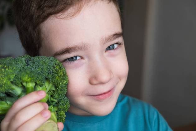 Creative Highlights Symbolbilder A cheerful young boy with sparkling eyes looks at the camera while playfully hiding half his face behind a stalk of fresh broccoli. The image captures a sense of fun and the importance of healthy eating for children. Model Released HelenaNechaeva_ID23271_676909_005 Copyright: xHelenaxNechaevax