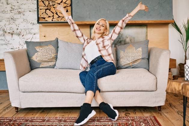 Glücklich lächelnde Frau mit erhobenen Händen sitzt auf dem Sofa zu Hause. Feiern Sie Erfolg Konzept Happy smiling woman with raised hands sitting on sofa at home. Celebrate succes concept Copyright: imageBROKER ViktorxGladkov ibxiqx09028086.jpg ,model released, Symbolfoto ,property released