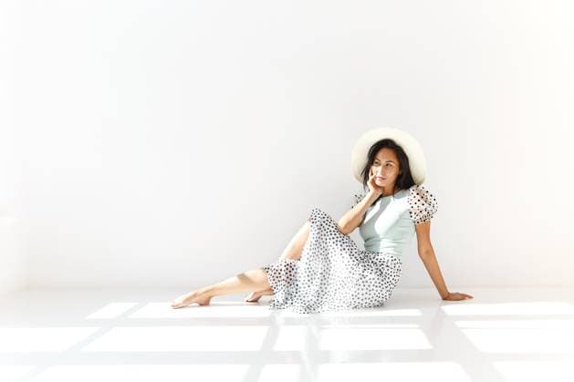 Seitenansicht einer jungen Asiatin in modischem Hut und Sommerkleid mit Polka Dot Ornament, die lächelt und in die Kamera schaut, vor weißem Hintergrund Side view of young Asian female in stylish hat and summer dress with polka dot ornament smiling and looking at camera against white background Copyright: imageBROKER DashaxPetrenko ibxiqx09195402.jpg ,model released, Symbolfoto ,property released