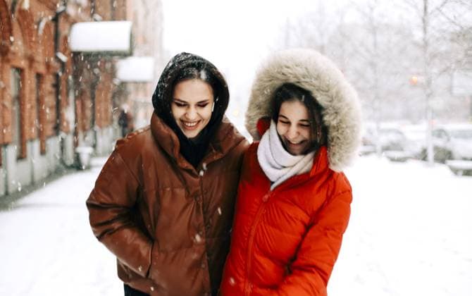Zwei glückliche Freundinnen genießen das verschneite Wetter im Freien, Frauen beste Freundinnen in Winterkleidung Daunenjacken lachen und haben Spaß beim Spaziergang auf Stadtstraße im Winter während der Weihnachtsferien Two happy female friends enjoying snowing weather outdoors, women best friends in winter clothes down jackets laughing and having fun while walking on city street in winter during Christmas holidays Copyright: imageBROKER DashaxPetrenko ibxiqx09195922.jpg ,model released, Symbolfoto ,property released