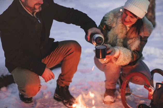 Joyful glückliche Familie Paar in der Liebe Sonnenbaden am Lagerfeuer draußen im Winter verschneiten Wald trinken heißen Tee zusammen, Mann und Frau wärmen sich umarmen und liebevollen Blick auf einander. Trekking, Abenteuer und saisonalen Urlaub Joyful happy family couple in love basking by campfire outside in winter snowy forest drinking hot tea together, man and woman warm themselves hugging and loving look at each other. Trekking, adventure and seasonal vacation Copyright: imageBROKER DashaxPetrenko ibxiqx09196081.jpg ,model released, Symbolfoto ,property released