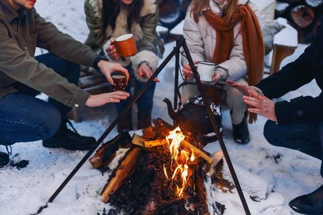 Eine Gruppe von Freunden versammelt sich um ein Lagerfeuer im Hinterhof, trinkt Tee und wärmt sich die Hände. Zwei glückliche Paare, die sich entspannen und die Wintersaison genießen, während sie am Feuer sitzen. Outdoor Winter unterhaltsam Group of friends gathering around bonfire in backyard, drinking tea and warming hands. Two happy couples relaxing and enjoying winter season while sitting around fire. Outdoor winter entertaining Copyright: imageBROKER DashaxPetrenko ibxiqx09201335.jpg ,model released, Symbolfoto ,property released