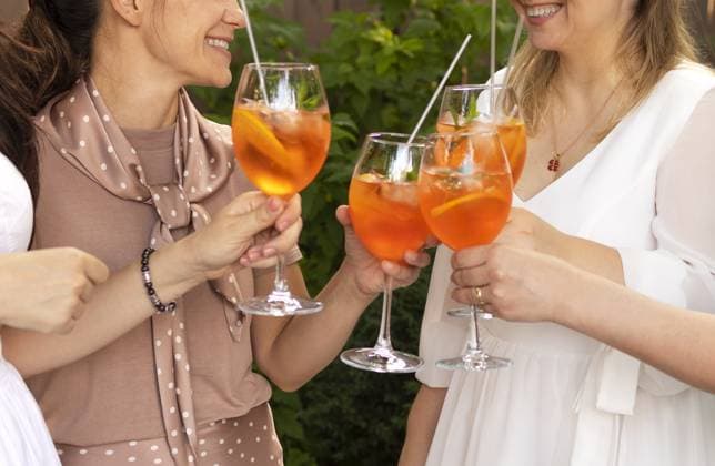 Glückliche Freunde verbringen Zeit miteinander, Fokus auf junge Frauen, die Aperol Spritz Cocktail trinken. Sommer Hochzeitsfeier. Fröhlichkeit und Feier Konzept Happy friends spending time together, focus on young women drinking Aperol spritz cocktail. Summer wedding party. Happiness and celebration concept Copyright: imageBROKER DashaxPetrenko ibxiqx09201833.jpg ,model released, Symbolfoto ,property released