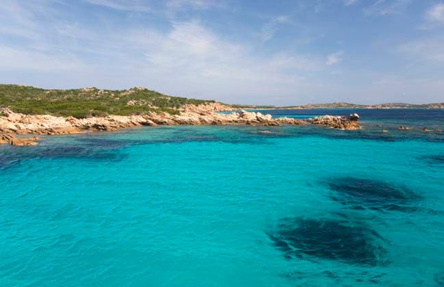View across clear turquoise water to rocky headland at northern end of the Spiaggia Rosa, Budelli Island, La Maddalena Archipelago National Park, Sassari, Sardinia, Italy, Mediterranean, Europe Copyright: DavidxTomlinson 1310-381 RECORD DATE NOT STATED