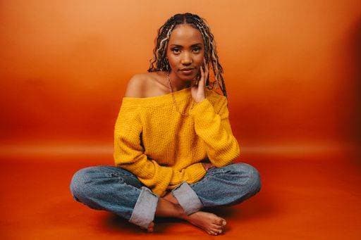 Creative Highlights Symbolbilder A stylish African American woman with long braids posing against an orange backdrop 25664985 ,model released, Symbolfoto RECORD DATE NOT STATED