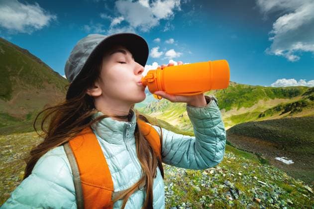 Creative Highlights Symbolbilder Profilfoto einer jungen schönen Frau mit langen blonden Haaren, bekleidet mit einer silbernen Jacke, die aus einer gelben Campingflasche trinkt, im Hintergrund eine herrliche Landschaft mit Bergen und Wolken Profile photo of a young beautiful woman with long blond hair, dressed in a silver jacket, drinking from a yellow camping bottle, in the background a magnificent landscape of mountains and clouds Copyright: imageBROKER IanxIankovskii ibxiqx09619725.jpg ,model released, Symbolfoto ,property released