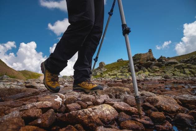 Wanderschuhe Nahaufnahme auf Bergfelsen am See mit Trekkingstöcken, Blick von unten Hiking boots close-up on mountain rocks by the lake with trekking poles, view from below Copyright: imageBROKER IanxIankovskii ibxiqx09619950.jpg