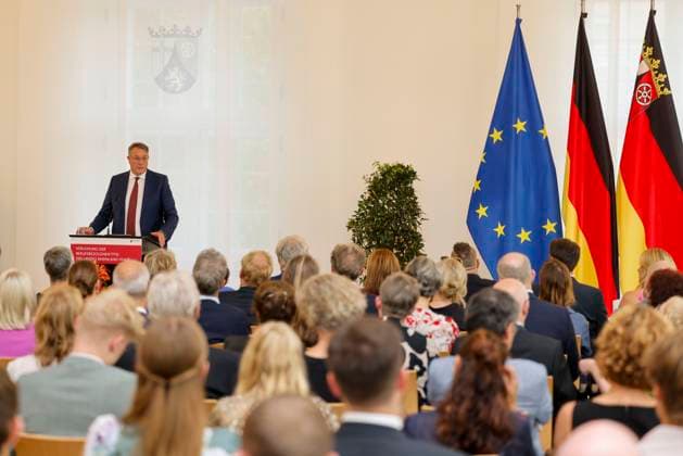 Der rheinland-pfälzische Ministerpräsident Alexander Schweitzer am Rednerpult vor Fahnen in der Staatskanzlei Rheinland-Pfalz. Rede anlässlich der verleihung berufsbezogener Titel des Landes. 03.09.24
