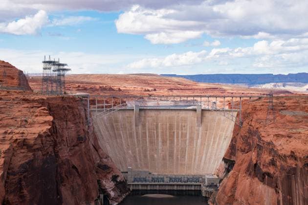 View of Enormous Glen Canyon Dam in Arizona With Scenic Red Rock Landscape - USA Stunning view of Glen Canyon Dam situated in Page, Arizona with Vehicles Driving Over. The image showcases the architectural marvel nestled within the scenic red rock cliffs under a cloudy sky - USA Copyright: xZoonar.com MadeleinexDeatonx 22076981