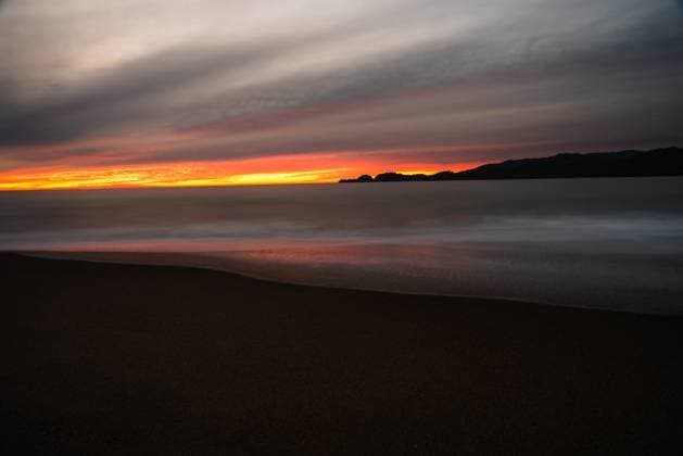 Creative Highlights World Moody sunset with a dark beach foreground and glowing horizon. San Francisco, California, United States R_OCZQ24090718-1461620-01