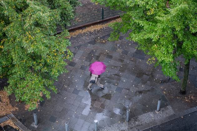 09.09.2024, Berlin, Deutschland, Europa - Eine Person mit Regenschirm geht an einem regnerischen Herbsttag eine nasse Strasse im Berliner Ortsteil Charlottenburg entlang. *** 09 09 2024, Berlin, Germany, Europe A person with an umbrella walks along a wet street in the Charlottenburg district of Berlin on a rainy fall day
