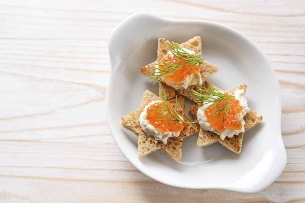 Canapes mit rotem Kaviar auf geröstetem Brot in Sternform mit Sahne und Dillgarnitur auf weißem Teller, heller Holztisch, Kopierraum, Blickwinkel von oben, gewählter Fokus Canapes with red caviar on toasted bread in star shape with cream and dill garnish on a white plate, light wooden table, copy space, high angle view from above, selected focus Copyright: imageBROKER MarenxWinter ibxiqx11040015.jpg