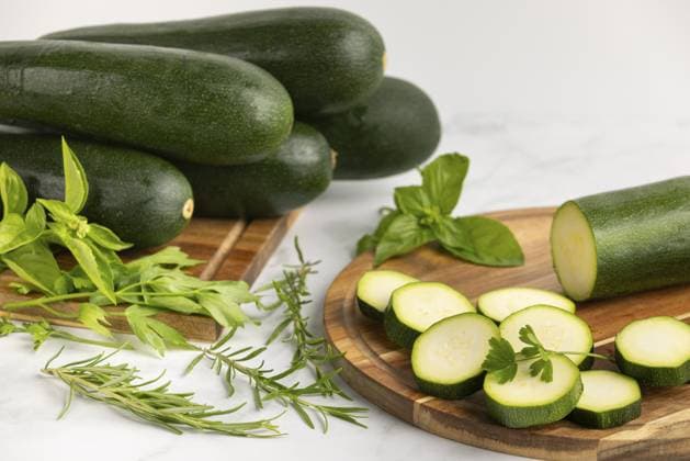 Sliced courgettes on a wooden board, with stacked courgettes and various fresh herbs next to them Copyright: imageBROKER LucasxSeebacher ibxlse11007859.jpg