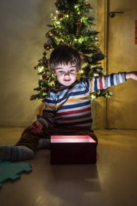 Creative Highlights Symbolfotos Ein kleiner Junge sitzt vor einem Weihnachtsbaum und öffnet eine rote Schachtel. Die Szene ist fröhlich und festlich, da der Junge von der Weihnachtszeit umgeben ist A young boy is sitting in front of a Christmas tree and opening a red box. Scene is joyful and festive, as the boy is surrounded by the holiday season Copyright: imageBROKER UnaixHuizi ibxuhu11262940.jpg ,model released, Symbolfoto ,property released