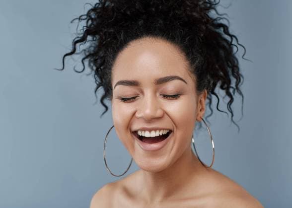 Creative Highlights Symbolfotos Portrait of laughing woman over gray backdrop. Happy female with curly hair and clean skin posing in studio with eyes closed. Portrait of laughing woman over gray backdrop. Happy female with curly hair and clean skin posing in studio with eyes closed. Copyright: xxx RECORD DATE NOT STATED