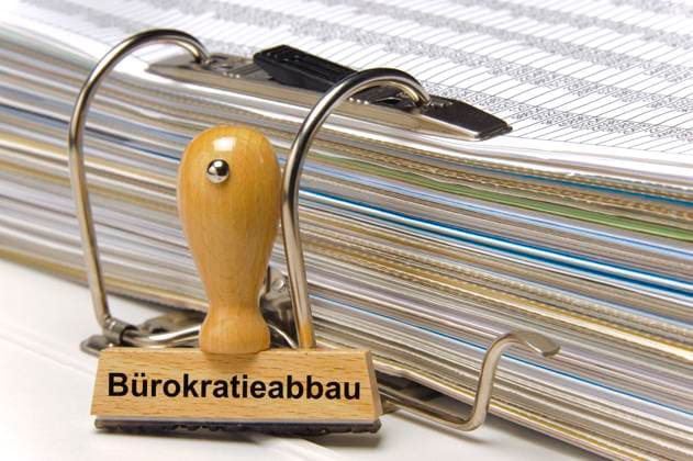Akten und Bürokratieabbau Ein Holzstempel ist beschriftet mit dem Aufdruck Bürokratieabbau *** Files and bureaucracy reduction A wooden stamp is inscribed with the words Bureaucracy reduction