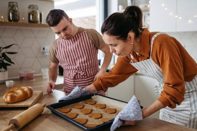 Young man with Down syndrome and his mom baking Christmas gingerbread cookies. Christmas peaceful moment for man with Down syndrome. Young man with Down syndrome and his mom baaking Christmas gingerbread cookies. Christmas peaceful moment for man with Down syndrome model released