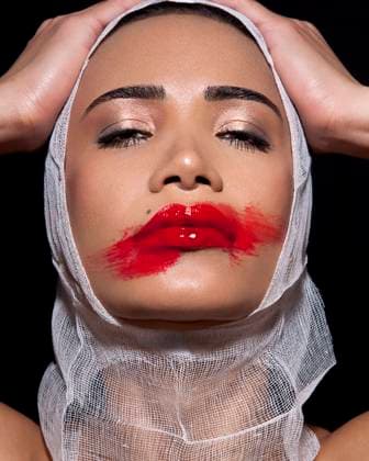 Creative Highlights Symbolfotos Close-up of a woman with dramatic red lipstick smeared across her face and a white bandage wrapped around her head, set against a black background. krst00255 Copyright: xConnectxImagesx ,model released