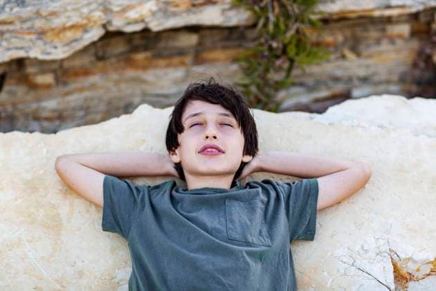 Creative Highlights Symbolfotos Handsome boy lying with eyes closed on the rock, vacation concept Çe?me, ?zmir, Türkiye R_THNZ240922-1545642-01 ,model released, Symbolfoto