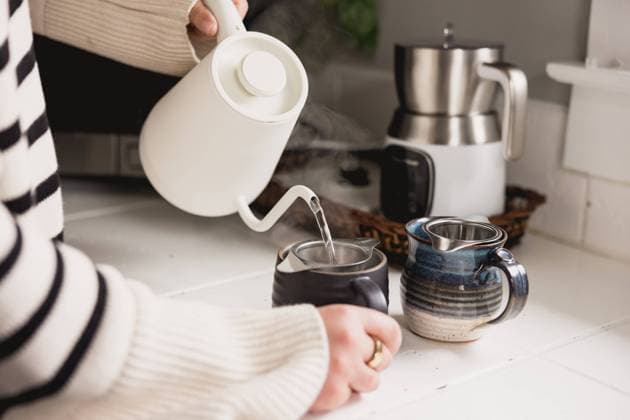 Woman in sweater pouring from a kettle into mugs with tea strainers Royal Oak, Michigan, United States R_YCQU240921C-1518450-01 ,model released, Symbolfoto