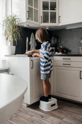 IMAGO Creative, Frühling, Frühjahrsputz Boy standing near sink and cleaning dishes at home model released, Symbolfoto property released, ELMF00782