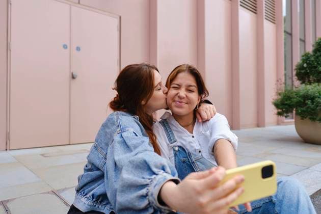 Young woman kissing girlfriend and taking selfie on sidewalk model released, Symbolfoto, ASGF05433