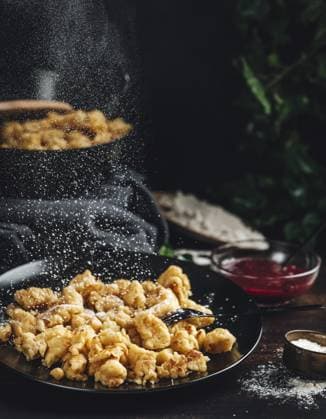 Kaiserschmarrn auf einem schwarzen Teller, wird mit Zucker bestreut, dunkler Hintergrund Kaiserschmarrn on a black plate, sprinkled with sugar, dark background Copyright: imageBROKER LucasxSeebacher ibxlse11423733.jpg