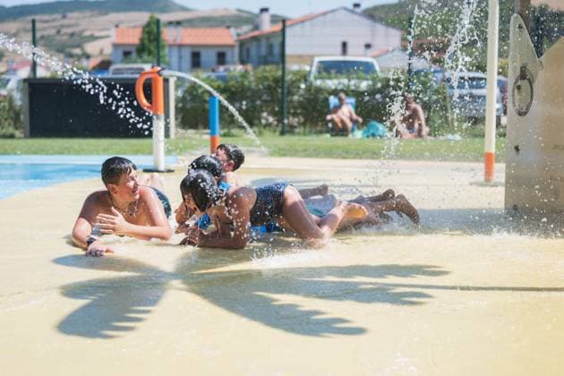 IMAGO Creative, Jahreszeit Sommer, Hitze Kids playing under a water spray in a pool area on a hot summer day, cooling off and splashing. The scene captures children lying prone and discussing excitedly, some looking at each other, engaged in lively conversations. Model Released HodeiUnzueta_ID23816_691396_004 Copyright: xHodeixUnzuetax