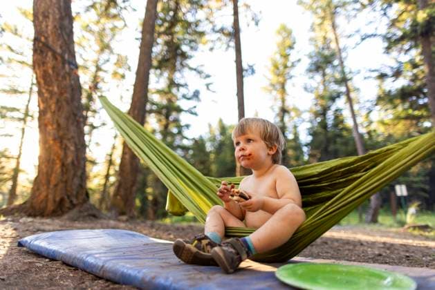 Creative Highlights Symbolfotos A toddler eats dinner while sitting in a hammock while camping. Libby, Montana, United States CR_XICZ240924-1539859-01 ,model released, Symbolfoto