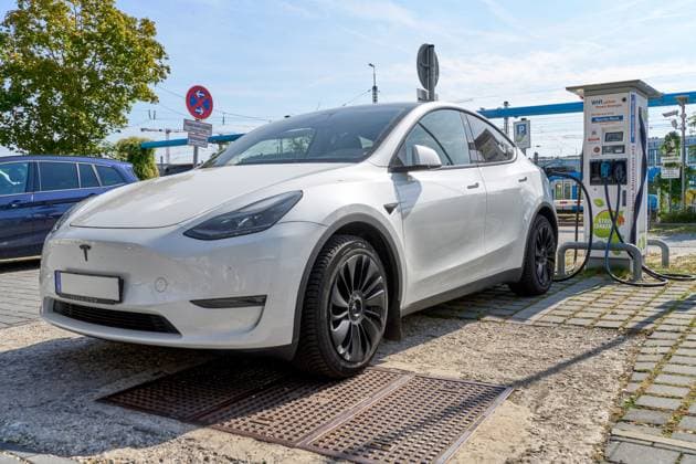 Ein weißer Tesla Model Y lädt an einer öffentlichen Ladestation in München