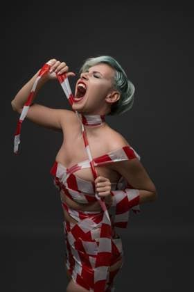 Nackte schreiende Blondine, eingewickelt in rotem und weißem Klebeband, abgeschnittene Aufnahme vor schwarzem Hintergrund Naked screaming blonde wrapped in red and white scotch tape cropped shot against black background Copyright: imageBROKER AndreyxGuryanov ibxgur11471002.jpg ,model released, Symbolfoto ,property released