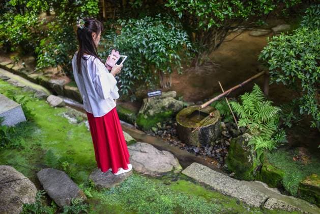 Young woman using smartphone at Ryoan-Ji Temple in Kyoto Copyright: xx NN-JAPAN2017-1153